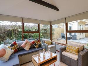 a conservatory with a couch and chairs and a table at Winding Wheel Cottage in Blythe