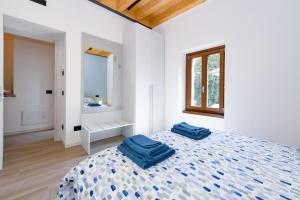 a white bedroom with two blue towels on a bed at Casa Contrada in Gargnano