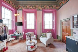 The Rose Nobel - 1 Bed Studio Apartment in Bristol by Mint Stays في بريستول: غرفة وردية مع كراسي وطاولة ونوافذ