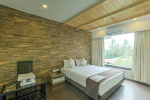 a bedroom with a bed and a brick wall at Crown Inn in Panvel