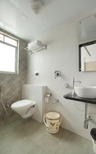 a white bathroom with a toilet and a sink at Crown Inn in Panvel