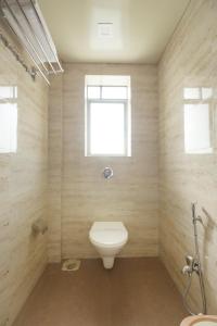 a bathroom with a toilet and a window at Crown Inn in Panvel