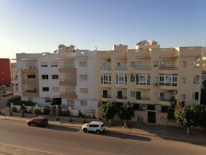 un immeuble d'appartements avec des voitures garées devant lui dans l'établissement Atomium, à Agadir
