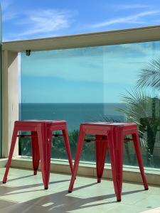 dos mesas rojas frente a una ventana con el océano en Căn hộ OCEAN 2PN view nhìn ra biển A212, en Ấp Ngọc Hải