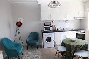 cocina con mesa, sillas y lavadora en Apartamento Mãe de Deus, en Ponta Delgada