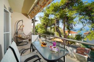 a balcony with a table and chairs and a swing at Sunside House in Skala Kallirachis