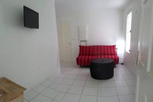 ein Wohnzimmer mit einem roten Sofa und einem TV in der Unterkunft PAPAYE VERTE habitation CALISSA in Bouillante
