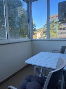 a table and chairs in a room with windows at Apartman Sidra in Trebinje