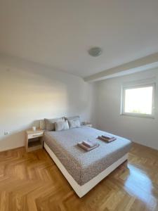 a white bedroom with a bed and a window at Apartman Sidra in Trebinje