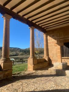 un edificio de piedra con techo de madera con columnas en Casa Bambolia, en Valdelinares
