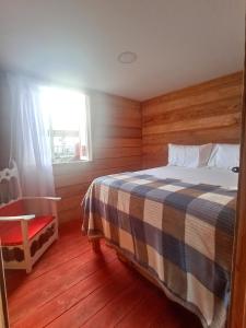 a bedroom with a bed with a checkered blanket and a window at Hotel Rancho El Vergel in Montenegro