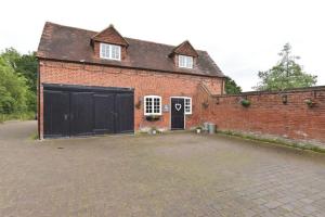 a brick building with a garage and a driveway at Amazing 100 year old church Rectory in Brentwood