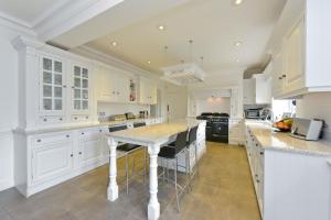 a kitchen with white cabinets and a island with bar stools at Amazing 100 year old church Rectory in Brentwood