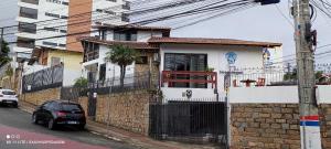 uma pequena casa branca com um carro estacionado em frente em Pousada Easy Floripa em Florianópolis