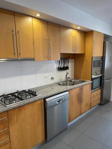 uma cozinha com armários de madeira e electrodomésticos de aço inoxidável em Penthouse Terrace Apartment em Ponta Delgada