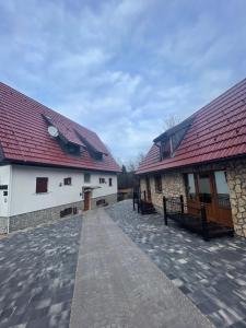 two buildings with red roofs and a walkway between them at Rustic Lodge Plitvice in Plitvička Jezera