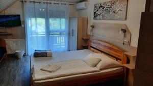Schlafzimmer mit einem großen Bett, einem TV und einem Fenster in der Unterkunft HARTMANN PANZIÓ in Barcs
