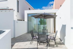 eine Terrasse mit einem Tisch, Stühlen und einem Sonnenschirm in der Unterkunft Forno da Cal Sea House in São Roque