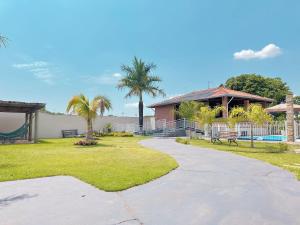 a walkway in front of a house with palm trees at Chácara dos Lopes in Brotas