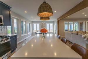 a kitchen with a large white table with a vase of orange flowers at Mountain Mama- Amazing Views! + Hot Tub! in Afton