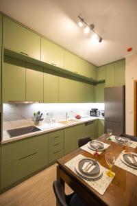uma cozinha com armários verdes e uma mesa de madeira em AKAKIA VILLA NAFPLIO em Nafplio