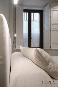 Cama blanca con almohada frente a una ventana en Luxury, Art and Deco apt para 4pax cerca de Plaza de España en Sevilla