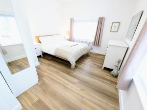 a bedroom with a bed and a wooden floor at Blossom Holiday Lets - 96 Roseberry Cottages in Guisborough