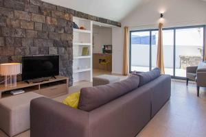 un soggiorno con un divano e una TV di Mosteiros Beach House a Mosteiros