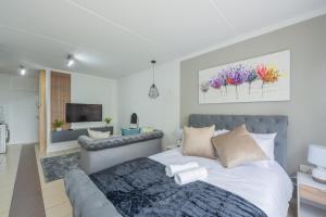 a bedroom with a bed and a living room at The Paddocks - Luxury Studio with Backup Power in Sandton