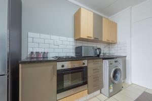 a kitchen with a stove and a washing machine at The Paddocks - Luxury Studio with Backup Power in Sandton