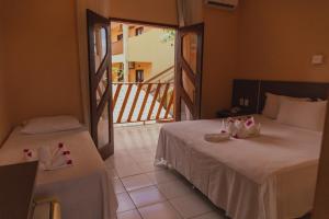a hotel room with two beds and a balcony at Pousada D' Areia in Barreirinhas