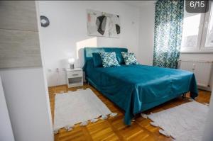 una camera da letto con un letto blu in una stanza bianca di SKY 1 APARTMAN a Subotica