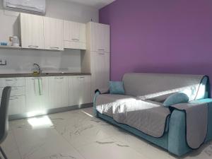 a room with a bed and a kitchen with purple walls at Le Ghie in Mondovì