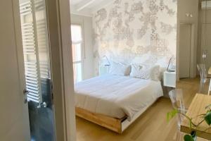 una camera con un letto bianco con una parete floreale di Le Terrazze 18 a Brescia