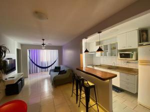 a kitchen and living room with a couch and a table at Ap Temporada Enseada Azul in Guarapari