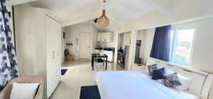 a white room with a bed and a kitchen at Lovely studio apartment with views of the lagoon. in Grand Baie
