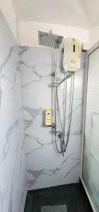 a shower in a bathroom with white marble walls at Lovely studio apartment with views of the lagoon. in Grand Baie