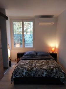 a bedroom with a bed and two windows at Studio avec Terrasse in Arles