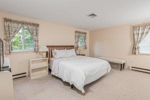 biała sypialnia z łóżkiem i 2 oknami w obiekcie Mill Pond Vista w mieście Chatham