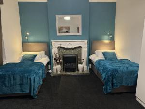 2 camas en una habitación con paredes azules y chimenea en Largee 5 Bed House, Sleeps 10 Near NEC, BHX, HS2, en Birmingham