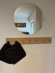 a mirror hanging on a wall with a black bag at Ferienwohnung AllgäuSchatz in Stadtnähe Kempten in Lauben