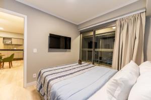 a bedroom with a bed and a large window at Apartamentos Studio Allure Moema - Com recepção 24 horas in Sao Paulo