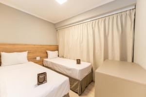 a small room with two beds and a window at Apartamentos Studio Allure Moema - Com recepção 24 horas in Sao Paulo