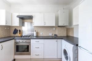 cocina con armarios blancos, fogones y lavavajillas en Wow Look Central 2bed Parking Next To Hospital en Southampton