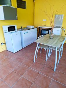 tavolo e sedie in cucina con pareti gialle di Studio avec terrasse et wifi a Le Marin a 5 km de la plage a Le Marin