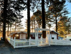 a white fence in front of a house with trees at The State Room - Cliffside, Ocean Views in Kodiak