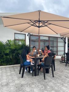 un grupo de personas sentadas en una mesa bajo un paraguas en HOTEL PLAYAS PERDERNALES ECUADOR, en Pedernales