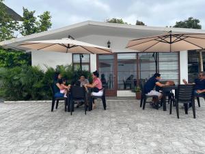 um grupo de pessoas sentadas em mesas sob guarda-chuvas em HOTEL PLAYAS PERDERNALES ECUADOR em Pedernales