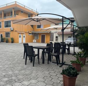una mesa y sillas con sombrillas en el patio en HOTEL PLAYAS PERDERNALES ECUADOR, en Pedernales