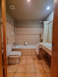 a bathroom with a toilet and a tub and a sink at Hostal y Apartamento Seixes in Bagergue